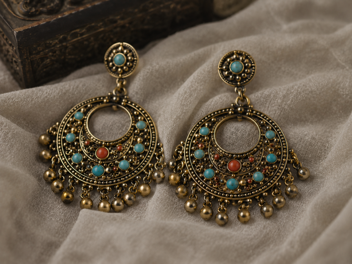 Gold chandelier earrings with gemstone clusters on linen
